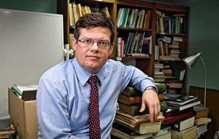 Krystian Markiewicz - prawnik Mężczyzna w koszuli i krawacie na tle półek z książkami