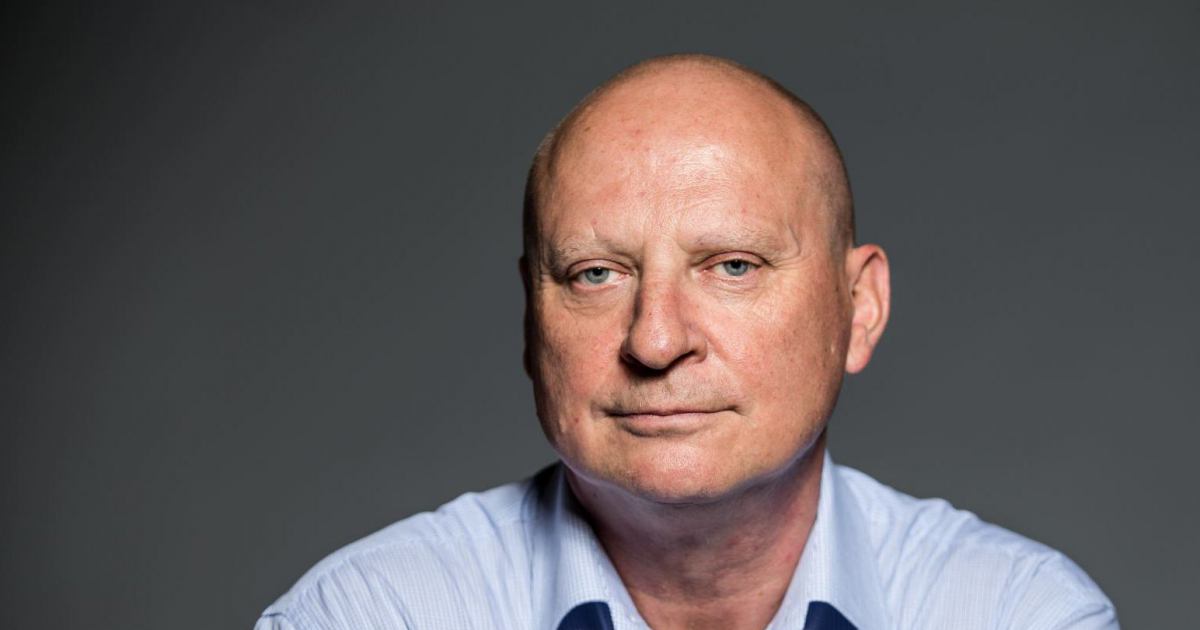 Prokurator Krzysztof Parchimowicz w niebieskiej koszuli, w ręku trzyma okulary