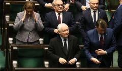 Jarosłąw Kaczyński stoi na swoim miejscu poselskim w Sejmie, patrzy w góre na wynik głosowania. Wokół niego Beata Mazurek i Mariusz Błaszczak