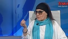 Temida Stankiewicz-Podhorecka w błęlitnym szalu, białej szacie i granatowej opasce na głowie