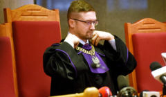 Mężczyzna w okularach w todze sędziowskiej z orłem na łańcuchu