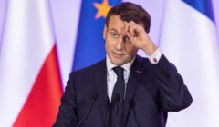 Prezydent Francji Emmanuel Macron na tle polskiej i unijnej flagi