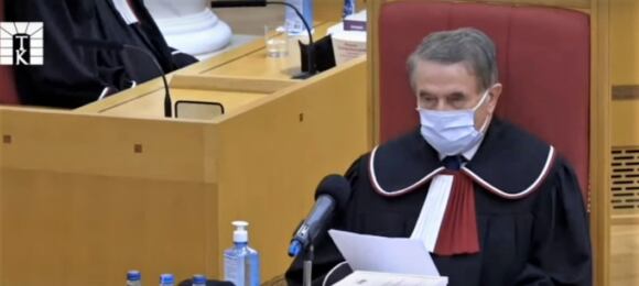 Leon Kieres w todze i maseczce odczytuje swoje zdanie odrębne