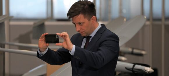 Michał Dworczyk fotofrafujący się na tle bojowego drona