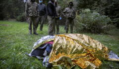 Uchodźcy na granicy polsko-białoruskiej chroniący się pod folią termoizolacyjną