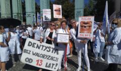 Lekarze dentyści trzymają transparent z napisem 