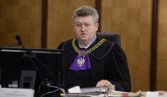 sędzia Krzysztof Chmielewski w todze i z łańcuchem sędziowskim prowadzi rozprawę w sądzie