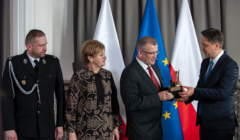 Cztery osoby na tle polskiej i unijnej flagi - RPO Marcin Wiącek wręcza nagrodę dla gminy Michałowo