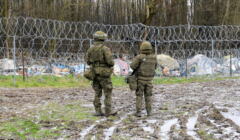 Żołnierze na granicy polsko-białoruskiej przez płotem z drutu kolczastego