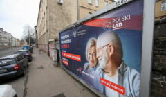 Billboard z parą uśmiechniętych starszych osób i napisem Polski Ład