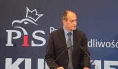 Paweł Kukiz na konferencji prasowej, w tle logo PiS