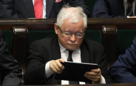 Jarosław Kaczyński czyta coś na tablecie w ławach sejmowych