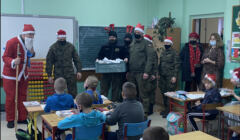 Żołnierze w czapkach mikołajów wnosza prezenty do klasy szkolnej