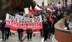 Marsz antyszczepiokowców, idą ulicą w Lublinie z transparentem 