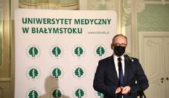 Minister Niefdzielski stoi na tle planszy z logo Unwersytetu Medycznego w Białymstoku