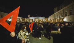 Protestująca młodzież z czerwonymi ekierkami i napisem „Wolna Szkoła