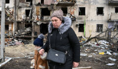 Ukraina. Matka z dzieckiem przed zniszczonym przez Rosjan blokiem mieszkalnym w Kijowie