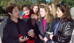 Kobieta w średnim wieku rozmawia z młodymi kobietami ubranymi w stylu lat 90.