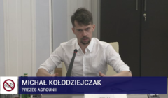 Michał Kołodziejczak w białej koszuli mówi do mikrofonu