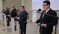 Czterej przedstawiciele NIK stoją przed mikrofonami