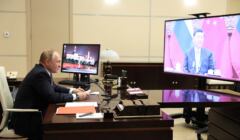 Putin siedzi w swoim gabinecie, na wielkim ekranie przed nim Xi Jinping