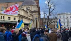 Ludzie idą ulica Stolarską w Krakowie. Niosą żółto-błekitne, ukraińskie flagi