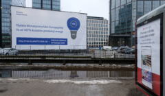 Biały baner z niebieską żarówką z namalowanymi na niej unijnymi gwiazdkami oskarżający UE o wzrost cen prądu