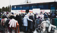 Grupa osób z bagażami stłoczona przy autobusie dalekobieżnym