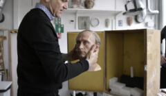 Męzczyzna wsadza do pudła rzeźbę głowy Putina