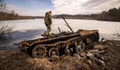 Ukraina, okolice Trościańca, 29.03.2022. Ukraiński żołnierz stoi na zniszczonym rosyjskim czołgu