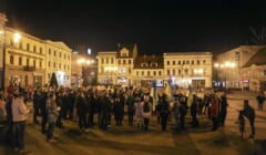 Ludzie stoją na ciemnym placu z flagami Ukrainy