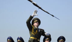 Oficer w galowym mundurze wykonuje akrobacje bronią