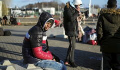 Czarnoskóry uchodźca z Ukrainy siedzi na betonowej barierze