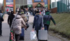 Ludzie z bagażami idą przez przejście graniczne