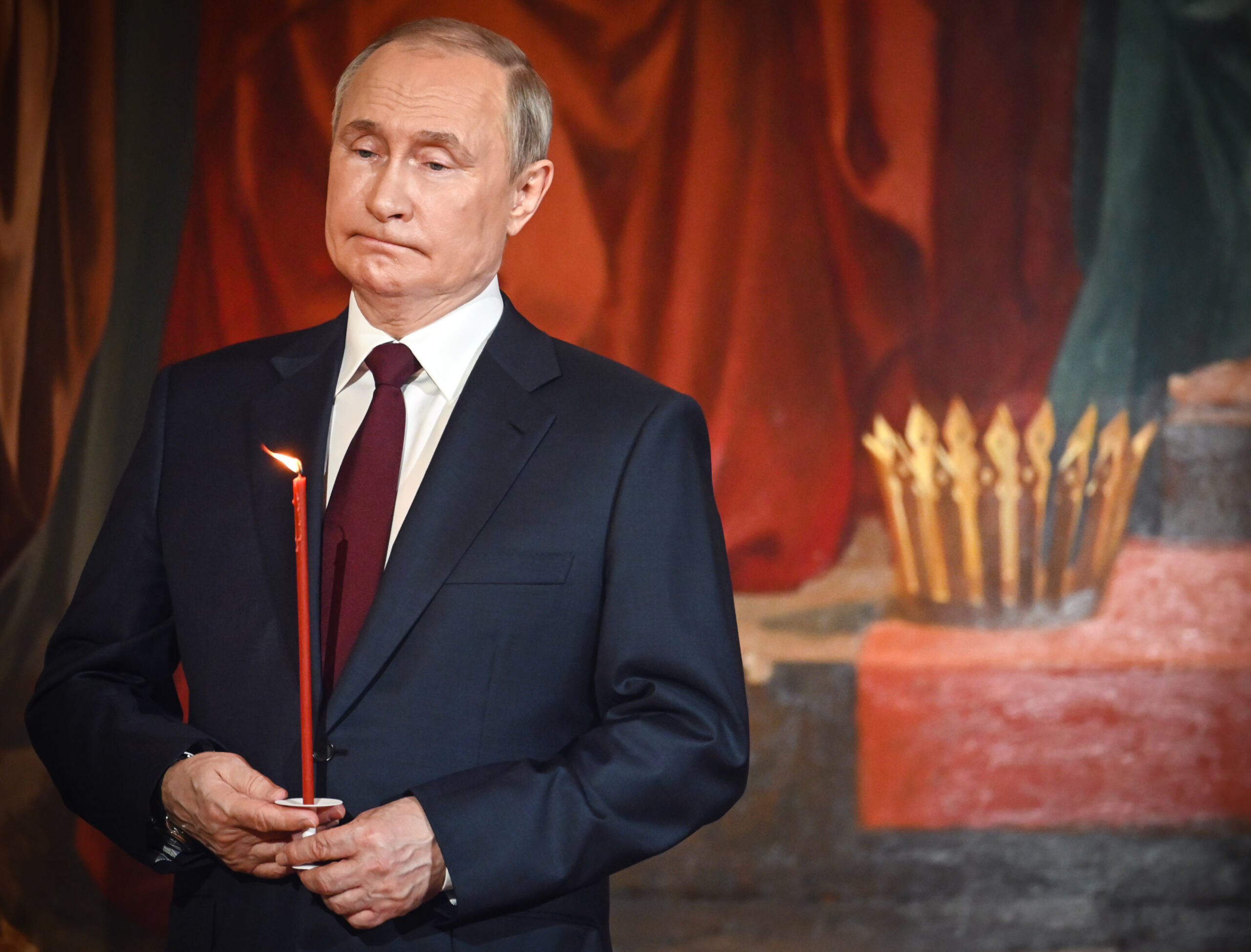 Putin w cerkwi trzyma cienką świecę w czasie nabozeństwa wielkanocnego