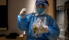 Chiński pielęgniarz w stroju ochronnym przygotowuje się do wykonania testu na COVID-19
