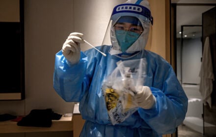 Chiński pielęgniarz w stroju ochronnym przygotowuje się do wykonania testu na COVID-19