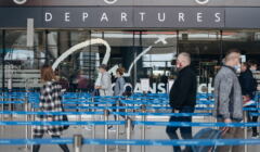 Lotnisko. Pasażerowie na tle napisu „Departures