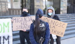 Trzy osoby z transparentami solidaryzującymi się z migrantami