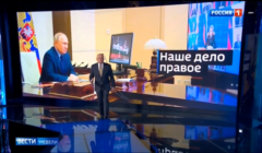Studio telewizyjne. Prowadzący na pierwszym planie, w tle - zdjęcie Putina prowadzącego telekonferencję