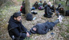 Grupa ludzi o bliskowschodnich rysach siedząca lub leżąca w lesie