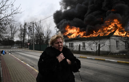 Kobieta płacze stojąc przed płonącym domem po tym, jak została ostrzelana w mieście Irpień pod Kijowem 4 marca 2022 r.