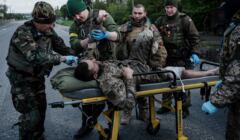 Ukraina, okolice Łysyczańska, 10.05.2022. Ukraińscy żołnierze, członkowie oddziału ewakuacyjnego, opatrują rannego żołnierza przed transportowaniem go do szpitala.