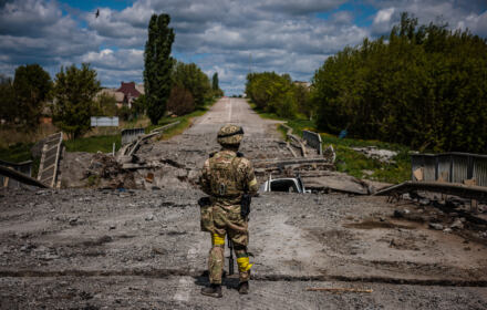 Żołnierz ukraińskiej jednostki specjalnej Kraken obserwuje teren przy zniszczonym moście na drodze w pobliżu wsi Ruśka Łozowa na północ od Charkowa, 16 maja 2022 r.