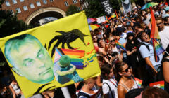 Ludzie na demonstracji z tranparentami z tarczą i podobizną Orbana