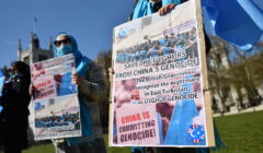 Kobiety z zasłoniętymi twarzami trzymają plakaty z wezwaniem do wsparcia walki Ujgurów z chińską opresją
