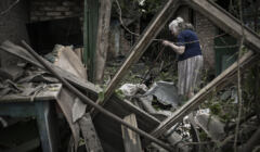 5 czerwca 2022 r. starsza kobieta z kotem na ramieniu próbuje oczyścić swoje podwórko z gruzu po uderzeniu pocisku, który zabił jedną starszą kobietę w mieście Drużkiwka na wschodzie Ukrainy, w regionie Donbas.