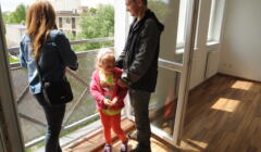 kobieta i mężczyzna z kilkuletnią dziewczynką wyglądają przez okno w nowowybudowanym mieszkaniu