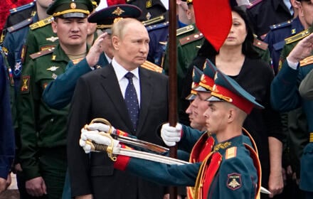 Mężczyzna w garniturze, przed nim żołnierze z wyciągniętymi paradnymi szablami, Władimir Putin