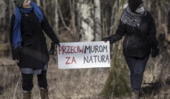 kobiety w lesie trzymające transparenty przeciw murowi na granicy polsko-białoruskiej